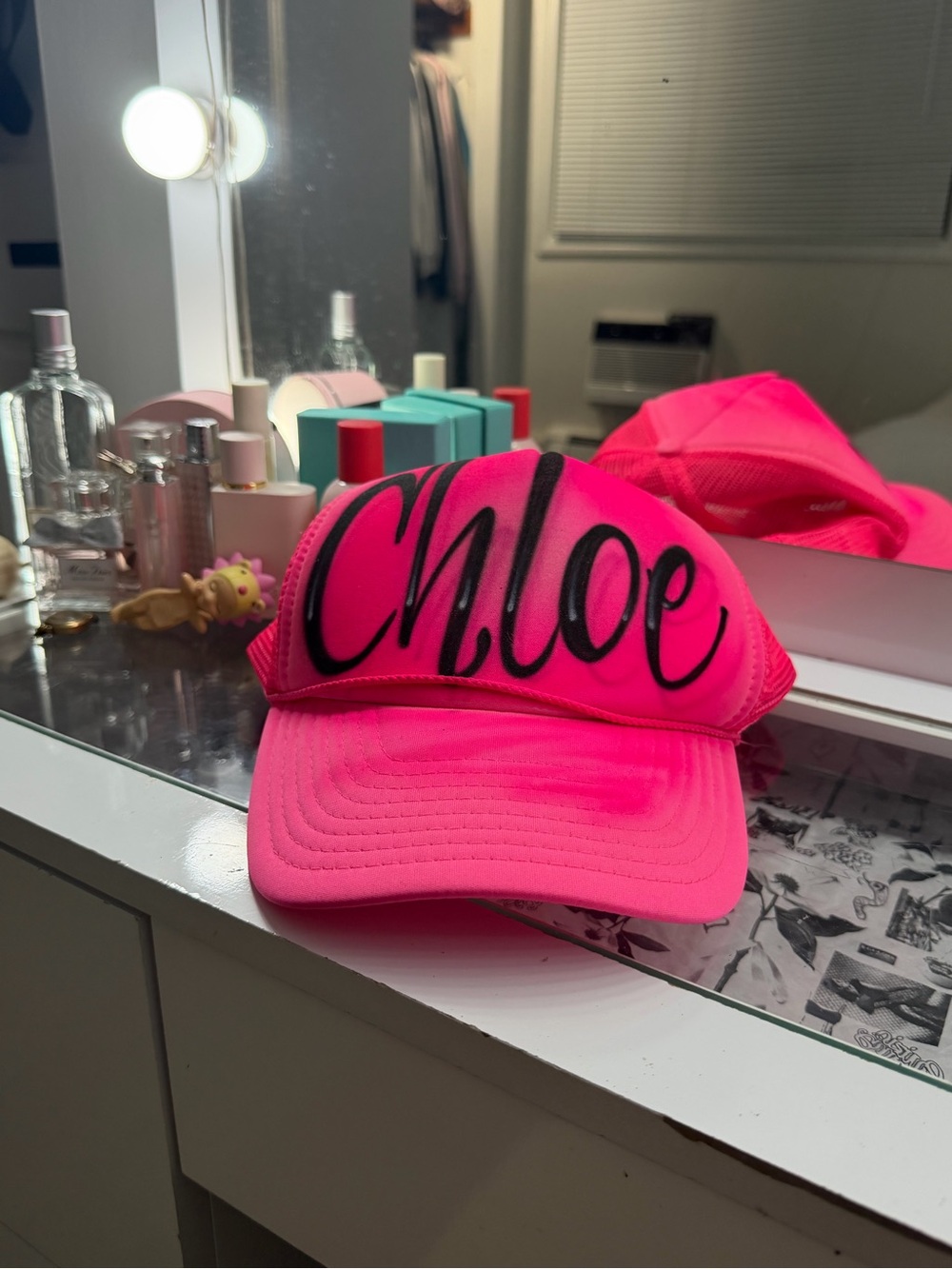 Hot pink trucker hat with “Chloe” in spray paint